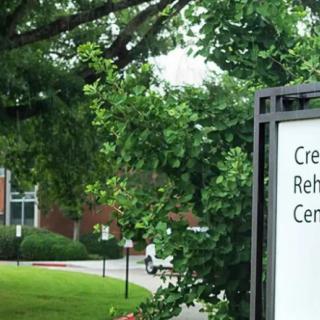 Sign for a rehabilitation center surrounded by trees and greenery.