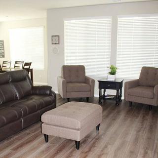 A modern living room with a dark sofa, two armchairs, and a coffee table, featuring elegant interior design.