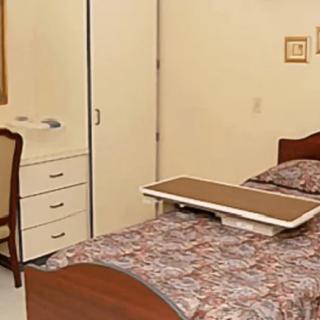 A cozy bedroom with a neatly made bed, a wardrobe, and a chair nearby.