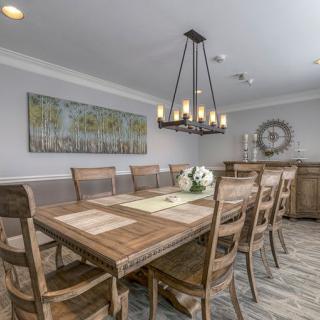 A modern dining room featuring a large wooden table, surrounded by chairs, and illuminated by a stylish chandelier.