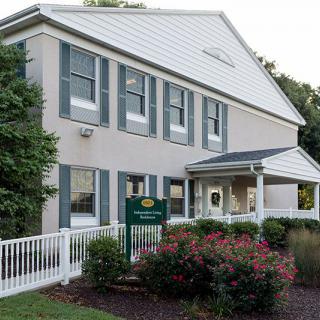A daycare center with a white fence, surrounded by well-maintained landscaping and bushes.