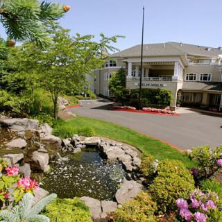A serene view of a building surrounded by lush greenery and a tranquil pond.