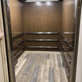The interior of a modern elevator with wood paneling and stylish flooring.