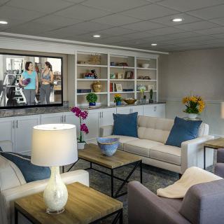 A modern living room with comfortable seating and stylish decor, featuring shelves filled with books and decorative items.