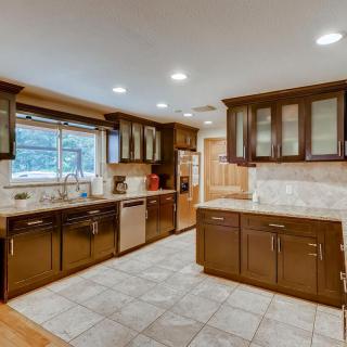 A spacious modern kitchen with wood cabinets and tile flooring.