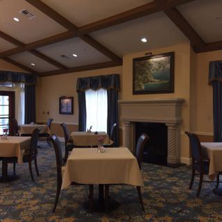 A cozy dining room with elegantly set tables and a fireplace.
