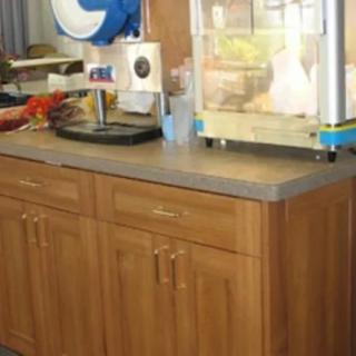A kitchen counter with a wooden cabinet, featuring a popcorn machine and snacks.