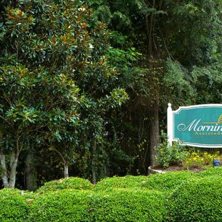 A scenic outdoor view featuring a sign surrounded by lush greenery and trees.