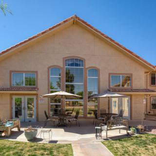 A spacious house with a large patio and outdoor seating area in the backyard on a sunny day.