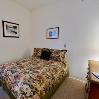 A cozy bedroom with a floral bedspread and wall art.