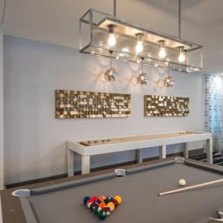 A stylish billiard room with a modern pool table, contemporary lighting fixtures, and decorative artwork on the walls.