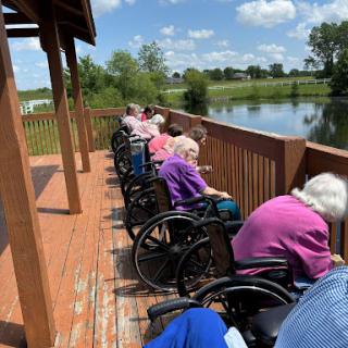 Elderly residents enjoying the serene view by the lake on a sunny day.