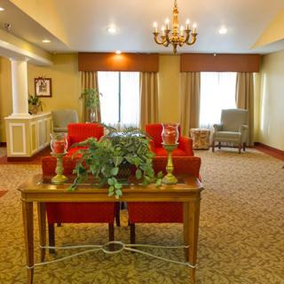 A well-decorated living room featuring red chairs, a chandelier, and a central table with plants.