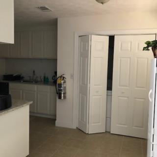 A clean kitchen interior with white cabinets and a partially open doorway.