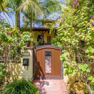 A tropical entrance to a house featuring lush greenery and a wooden gate.