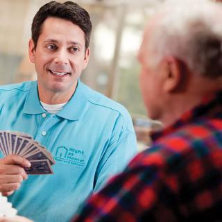 A caregiver and an elderly person enjoying a card game together.