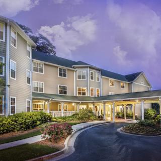A residential building with a driveway under a twilight sky.