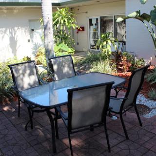 A cozy outdoor dining area with a glass table and chairs surrounded by greenery.