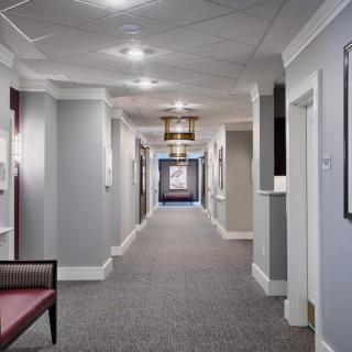 A well-lit hallway with carpet flooring and multiple doors on either side.