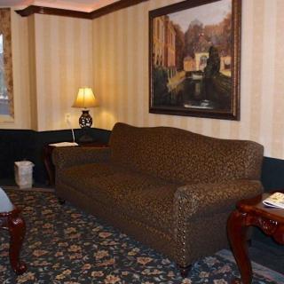 A cozy living room with a patterned sofa, side tables, a lamp, and a decorative painting on the wall.