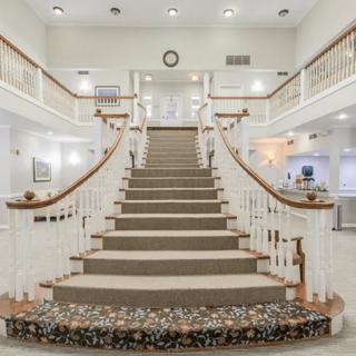 An elegant, symmetrical indoor staircase with white railings and soft lighting.