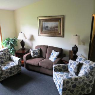 A cozy living room with a sofa, two patterned armchairs, and decorative lamps.