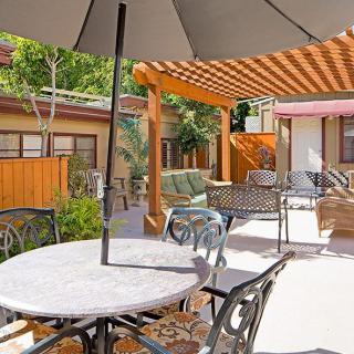 A cozy outdoor patio area with tables, chairs, and a pergola.