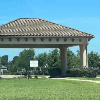 A pavilion with a tiled roof surrounded by greenery on a clear day.