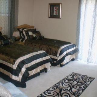 A cozy bedroom with two neatly made single beds, featuring black and white striped bedding and a patterned carpet.