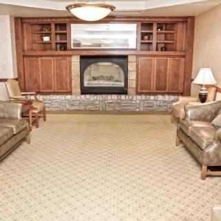 A cozy living room with a fireplace, sofas, and wood paneling.