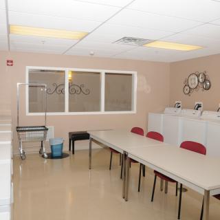 A clean and organized laundry room with tables and chairs.