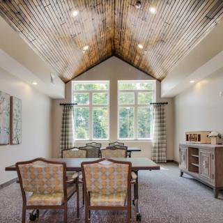A dining room with a wooden ceiling, large windows, and elegant furniture.