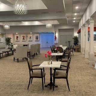 A spacious and elegantly decorated lobby with tables, chairs, and a chandelier.