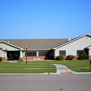 A well-maintained residential building with a green lawn and clear blue sky.
