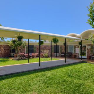 A modern outdoor patio area with vibrant green grass and clear blue skies.
