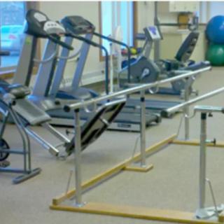 A rehabilitation gym with exercise equipment including treadmills and parallel bars.
