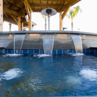 An outdoor spa pool featuring cascading waterfalls under a gazebo.