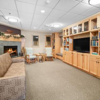 A cozy living room area featuring a fireplace, comfortable seating, and bookshelves.