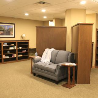 A cozy lounge area featuring a gray sofa and wooden shelves, perfect for relaxation.