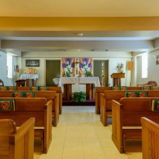 Interior view of a small church with wooden pews and an altar.