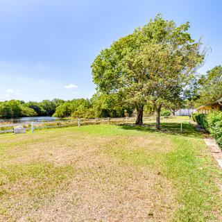 A scenic view of a grassy area with trees near a river under a clear blue sky.