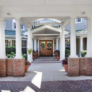 A welcoming entrance to a building with white columns and brick accents.