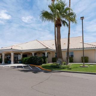 A suburban building with palm trees under a partly cloudy sky.