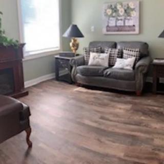 A cozy living room with a sofa, chairs, and a fireplace, featuring elegant decor and hardwood flooring.