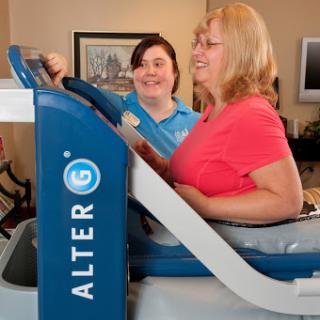 A healthcare professional assists a patient during a rehabilitation exercise using specialized equipment.