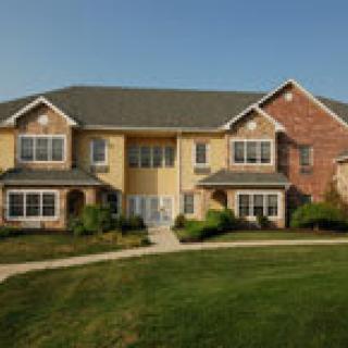 A suburban residential building with a well-maintained lawn under a clear blue sky.