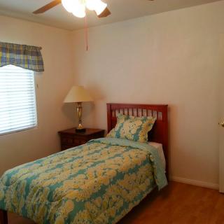 A cozy bedroom with a single bed, dressed in floral bedding, and a wooden nightstand beside it.