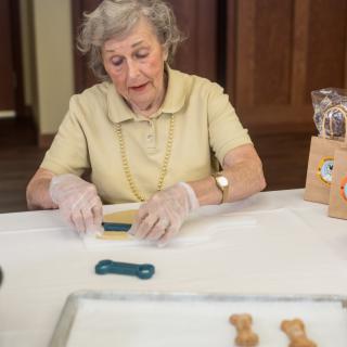 An elderly woman crafting homemade dog treats in the kitchen.