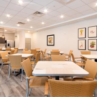 A modern cafeteria with neatly arranged tables and chairs, bright lighting, and decorative artwork on the walls.