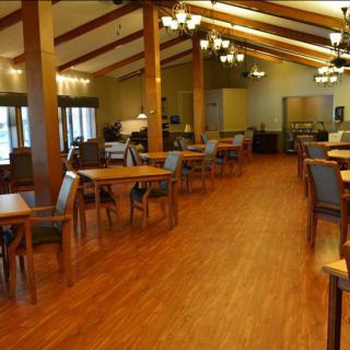 A cozy dining area with wooden flooring, tables, and chandeliers.